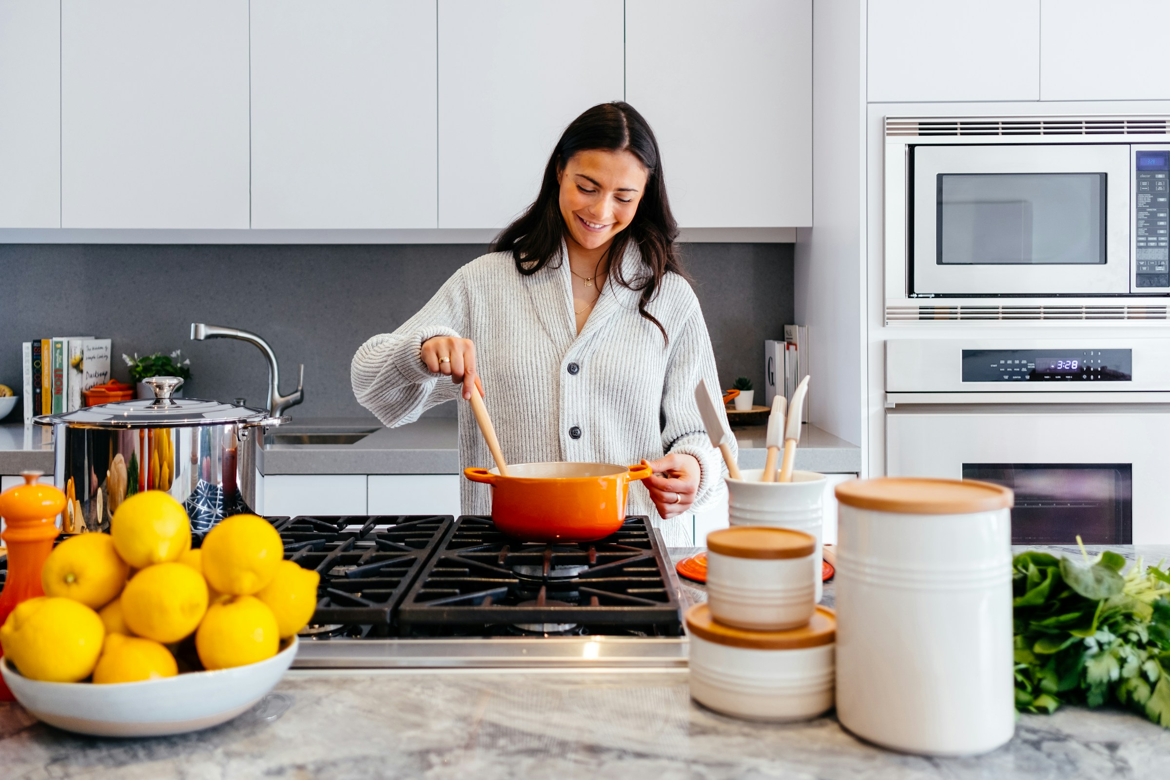 Smiling woman cooking in a modern kitchen with built-in oven appliances