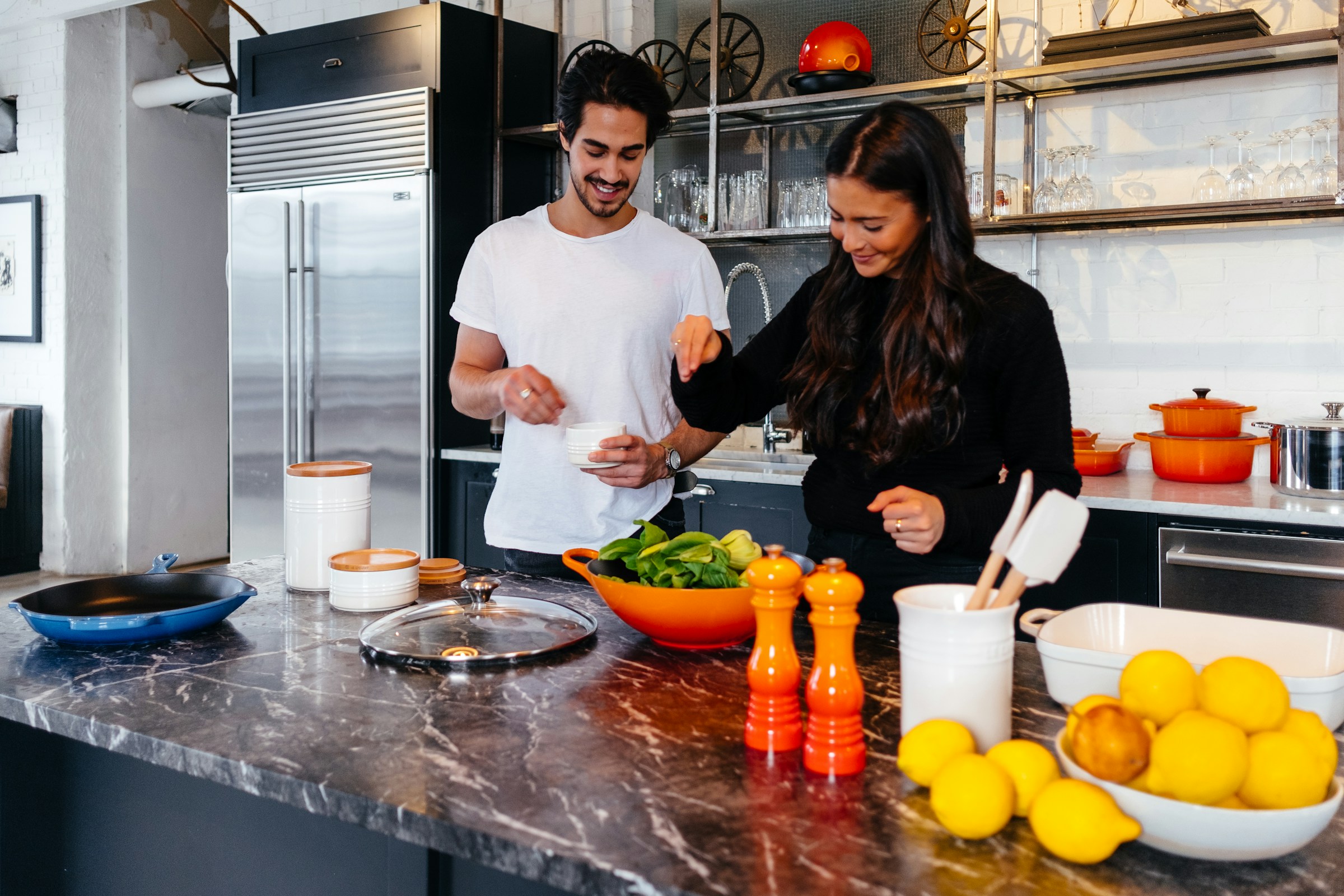 Smiling couple in a modern premium kitchen with luxury refrigerator